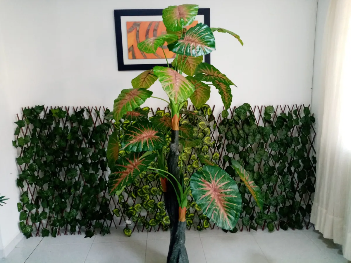 Malla de hiedra artificial detrás de una planta de hojas grandes